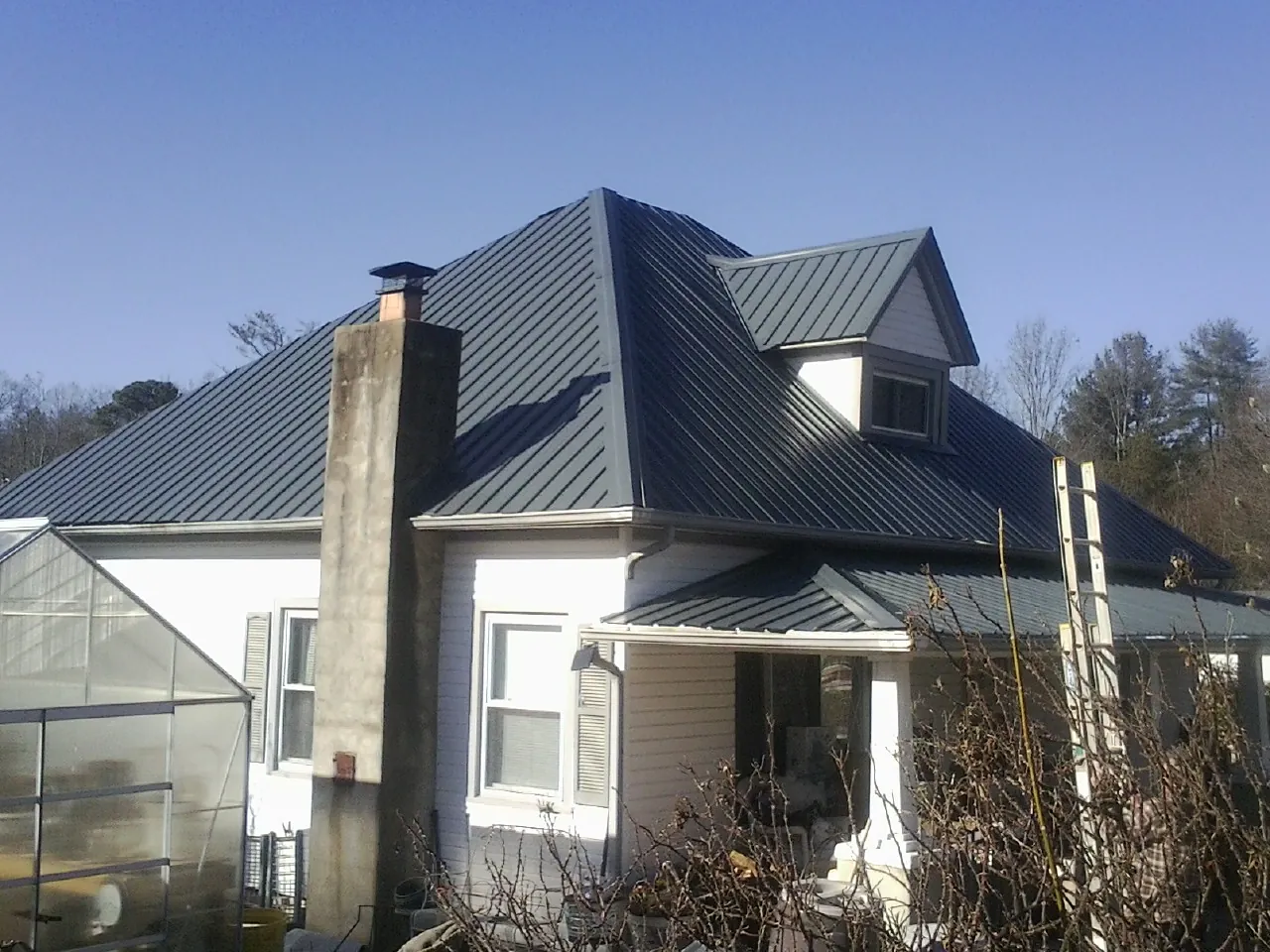Dark blue standing seam metal roof on a white farmhouse with dormer — Slate & Tile Roof Repair by Roofing Brothers in Koosharem