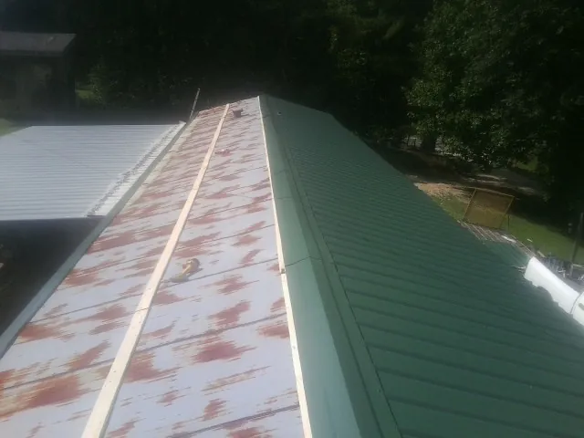 Old rusted panels beside newly installed green metal roofing — Wind Damage Roof Repair by Roofing Brothers in Koosharem