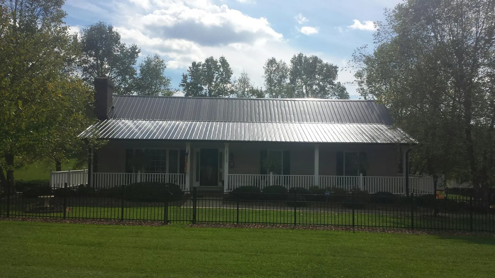 Gray metal roof on a brick ranch with a full width front porch — Gutter Guard Installation work by our crew in Koosharem