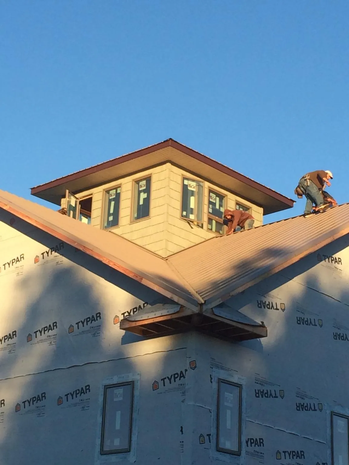 Roofers working around a rooftop cupola on a new metal roof at sunset — Roof Waterproofing in Koosharem by Roofing Brothers